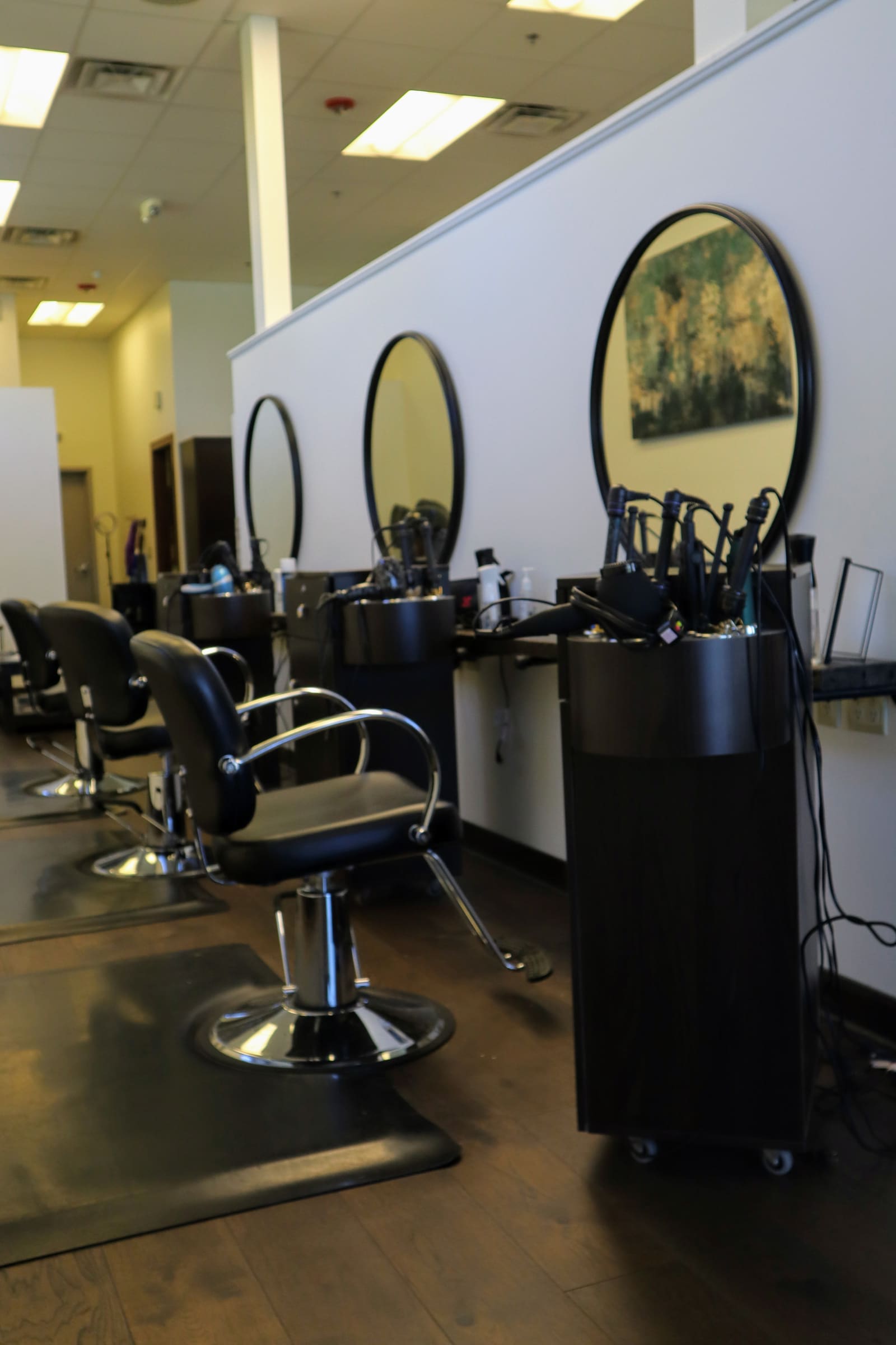Styling stations at Salon Marie with round black mirrors and a row of salon chairs